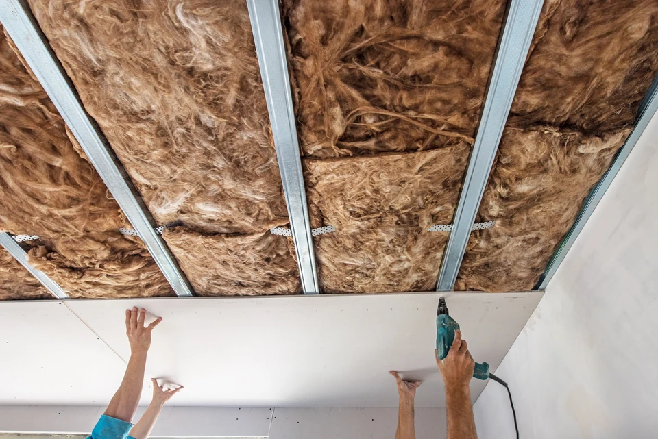 Chantier de rénovation intérieur avec ouvrier installant un plafond suspendu