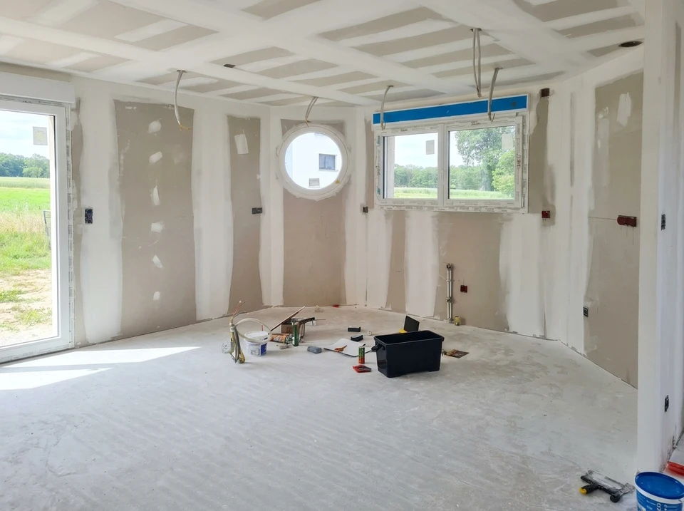 Personne appliquant de la peinture blanche sur un mur intérieur avec un pinceau plat